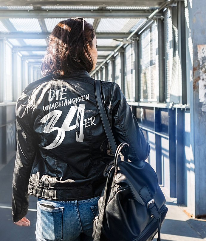Frau mit #DIE34ER Lederjacke auf Brücke