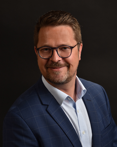 Christian König, ein sympathischer Herr mittleren Alters mit braunem Haar, Bart und dunkelblauem Anzug